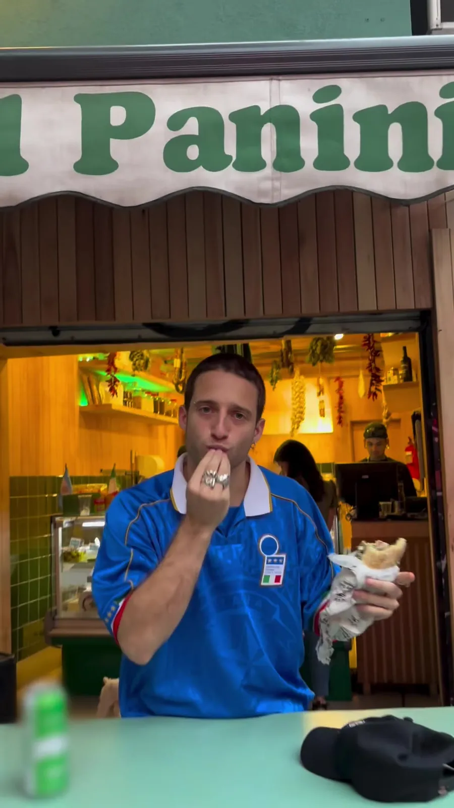Un cliente con la camiseta de Italia hace el gesto del beso del chef frente al local