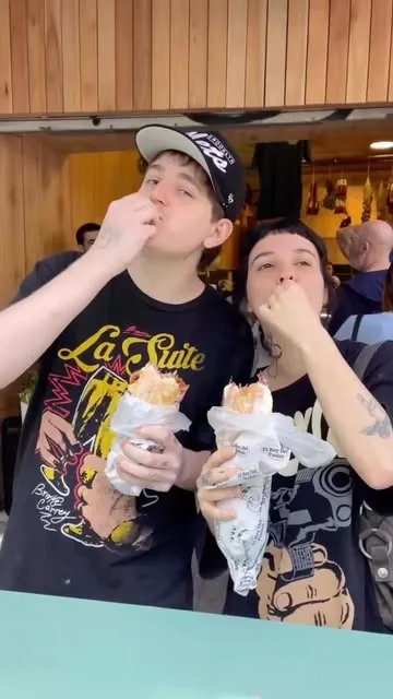 Dos clientes hacen el gesto del beso del chef con sus paninis