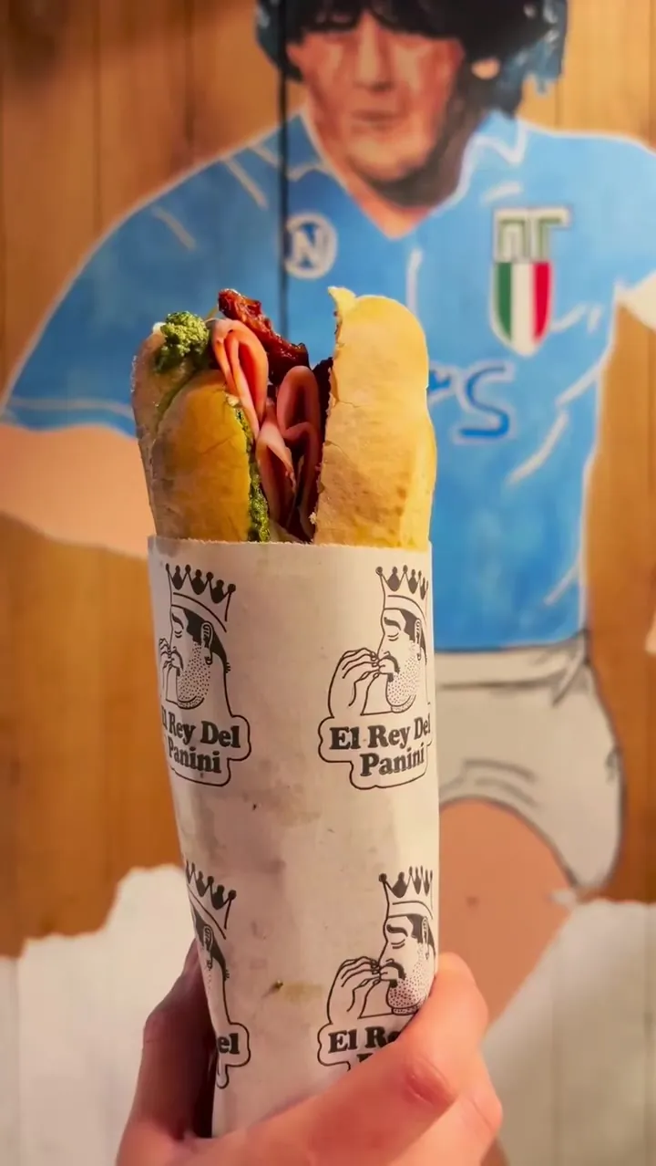 Panini envuelto en el papel de El Rey Del Panini, con mortadela y pasta de pistachos